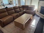 Brown leather sectional sofa with matching wooden coffee table in a living room.